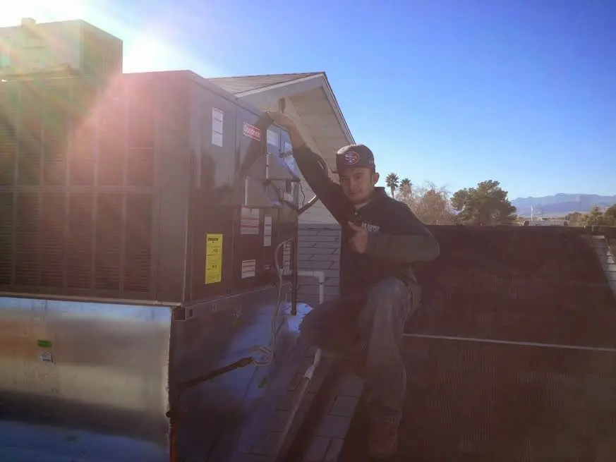 HVAC technician performing AC Tune-Up on a rooftop unit in Dallas